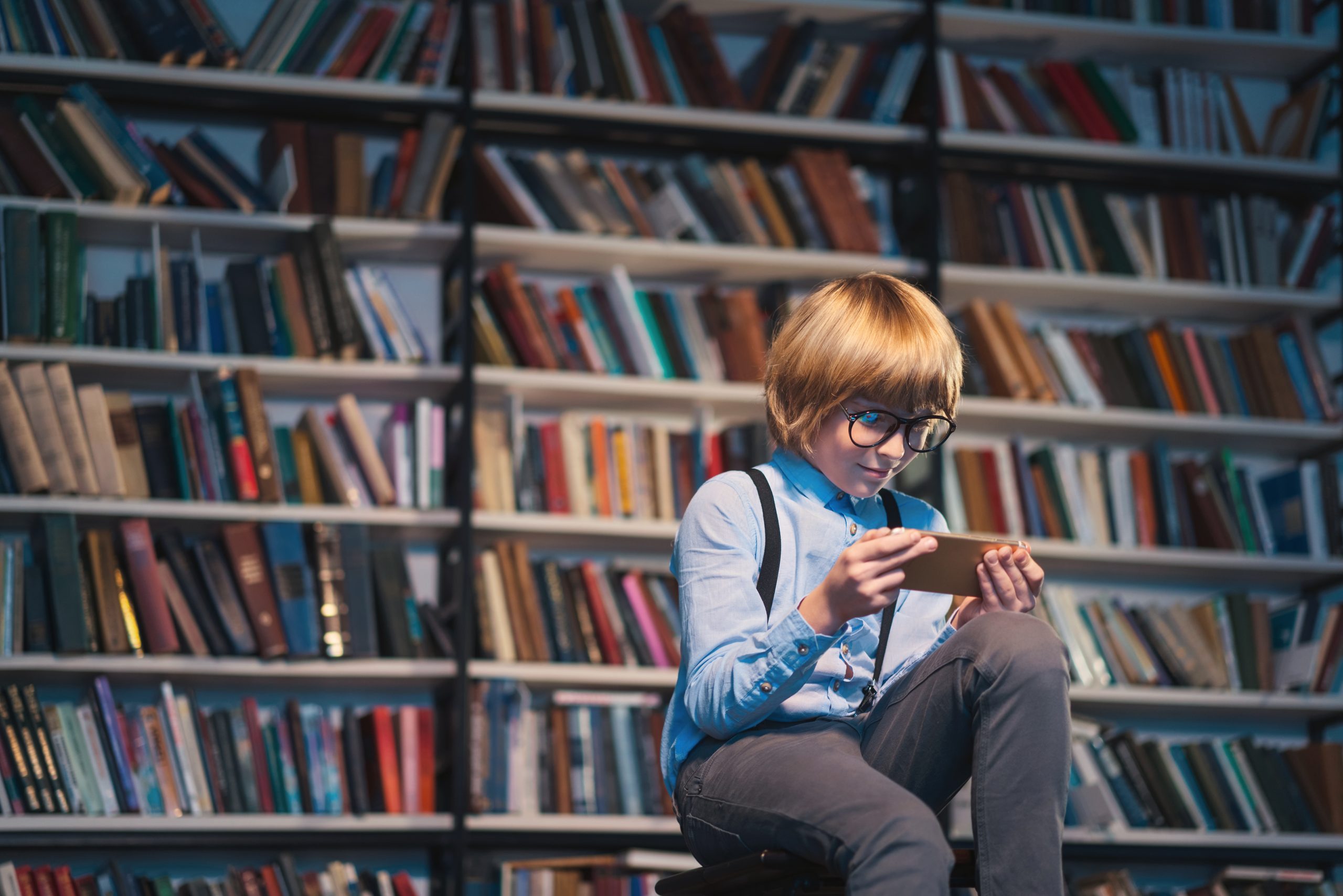 Boy with a phone in library